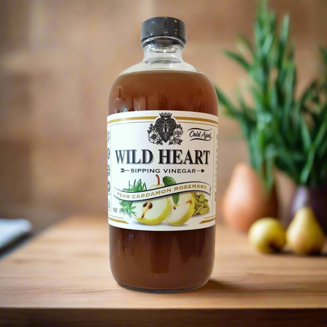 Wild Heart Pear Cardamom Rosemary sipping vinegar bottle on a kitchen counter with pears and rosemary